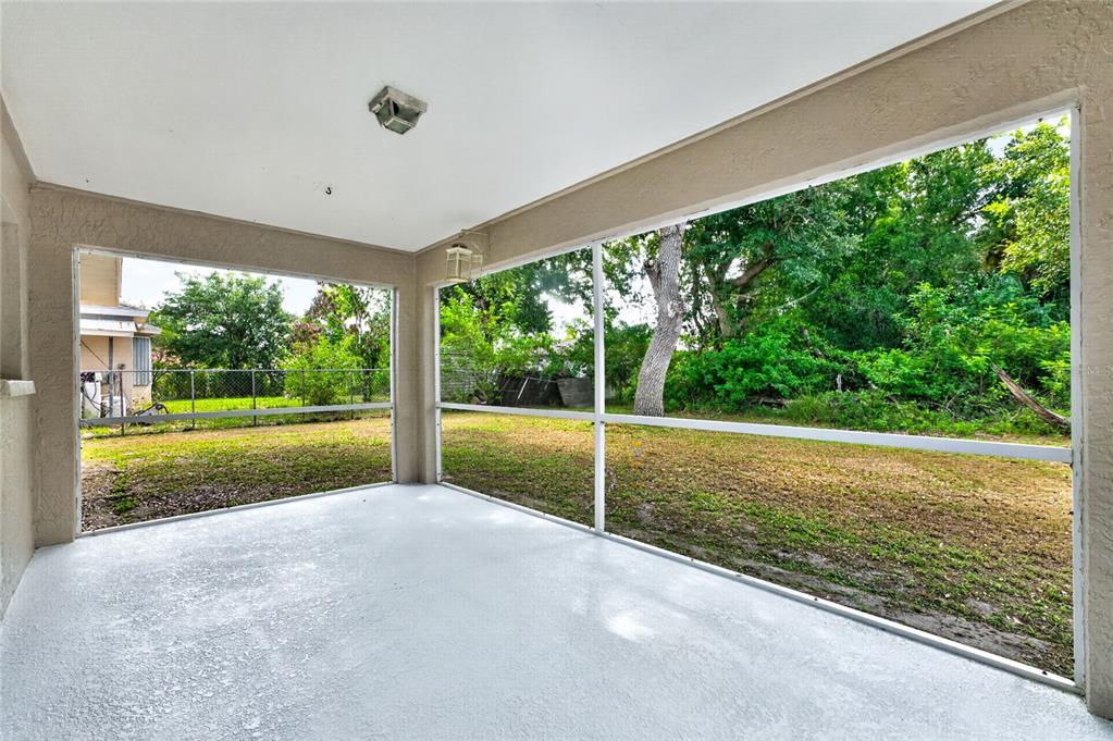 A screened-in porch with a painted concrete floor overlooks a grassy backyard with trees — 4436 MAURBACH TERRACE, NORTH PORT, FL