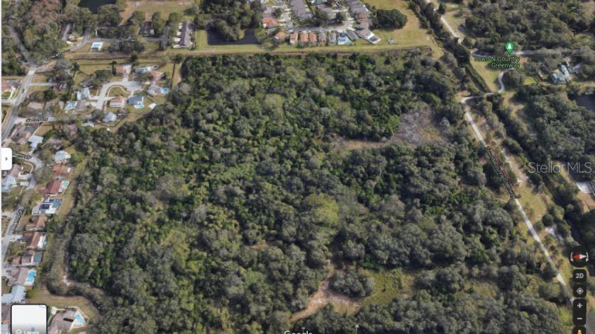 An aerial view shows a large, wooded plot of land surrounded by residential neighborhoods — ARMAND DRIVE, TAMPA, FL
