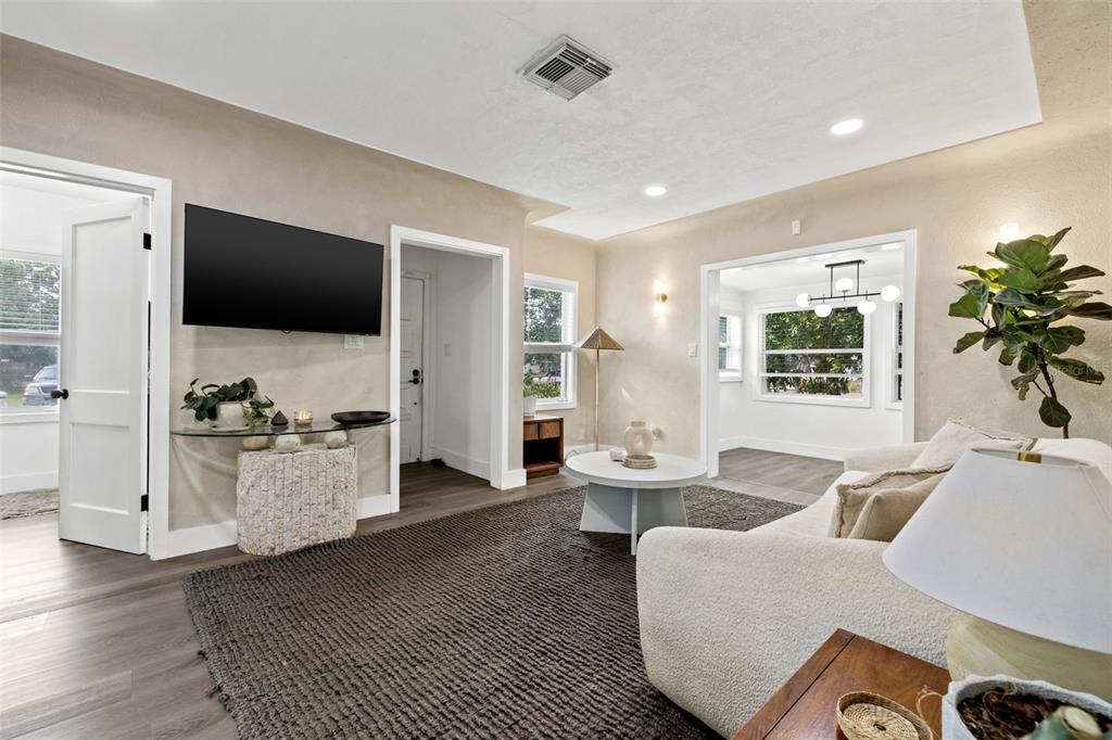 A living room features a wall-mounted television, a glass console table, and a white sofa — 3731 6TH AVENUE N, ST PETERSBURG, FL