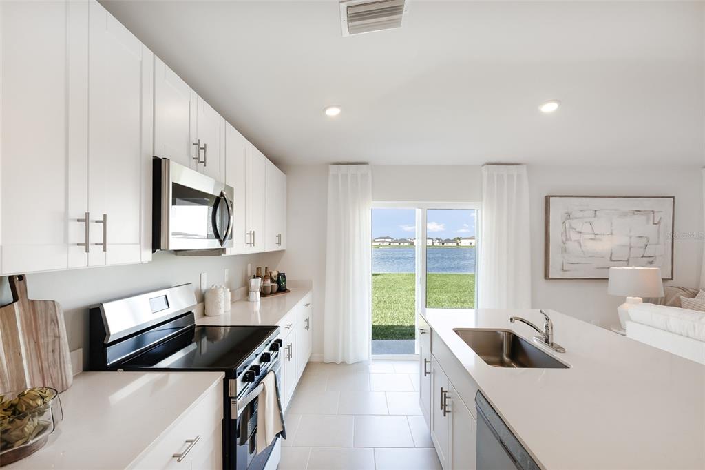 A modern kitchen features white cabinets, stainless steel appliances, and a central island with sink — 1358 FARGO STREET, PORT CHARLOTTE, FL