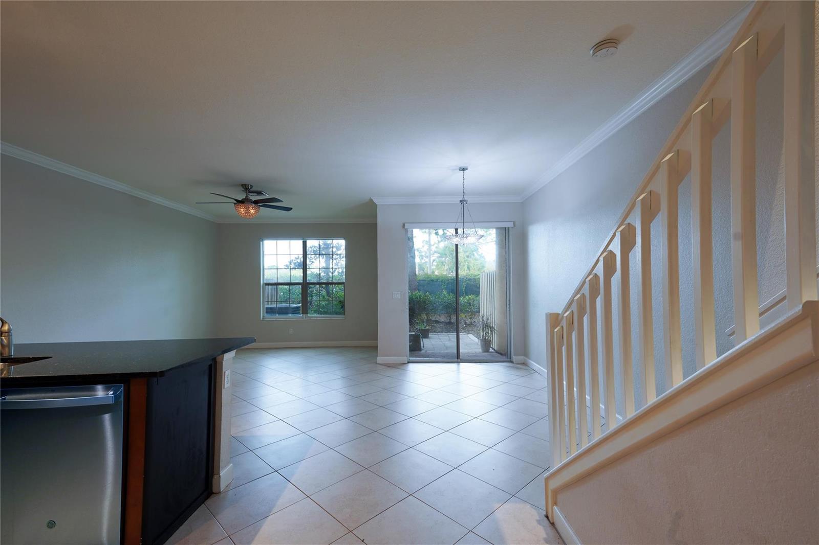 An open-concept living area features tile flooring, a staircase, and a sliding glass door — 5045 Ellery Terrace, West Palm Beach FL 33417, WEST PALM BEACH, FL