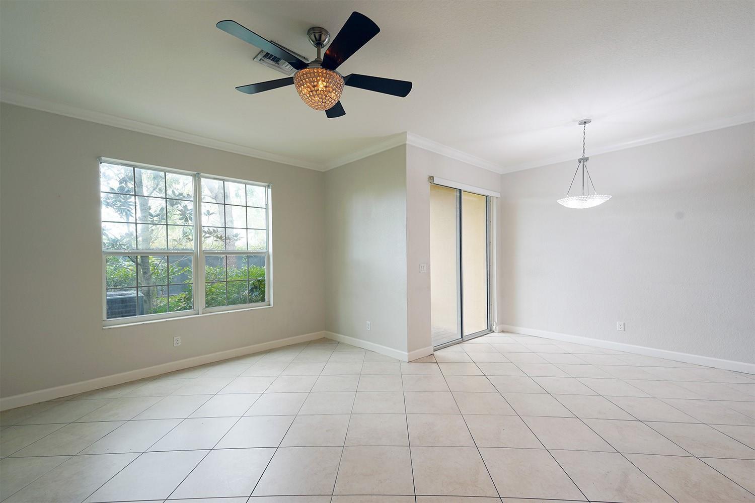 An empty room with light tile flooring, a crystal ceiling fan, and a sliding glass door — 5045 Ellery Terrace, West Palm Beach FL 33417, WEST PALM BEACH, FL