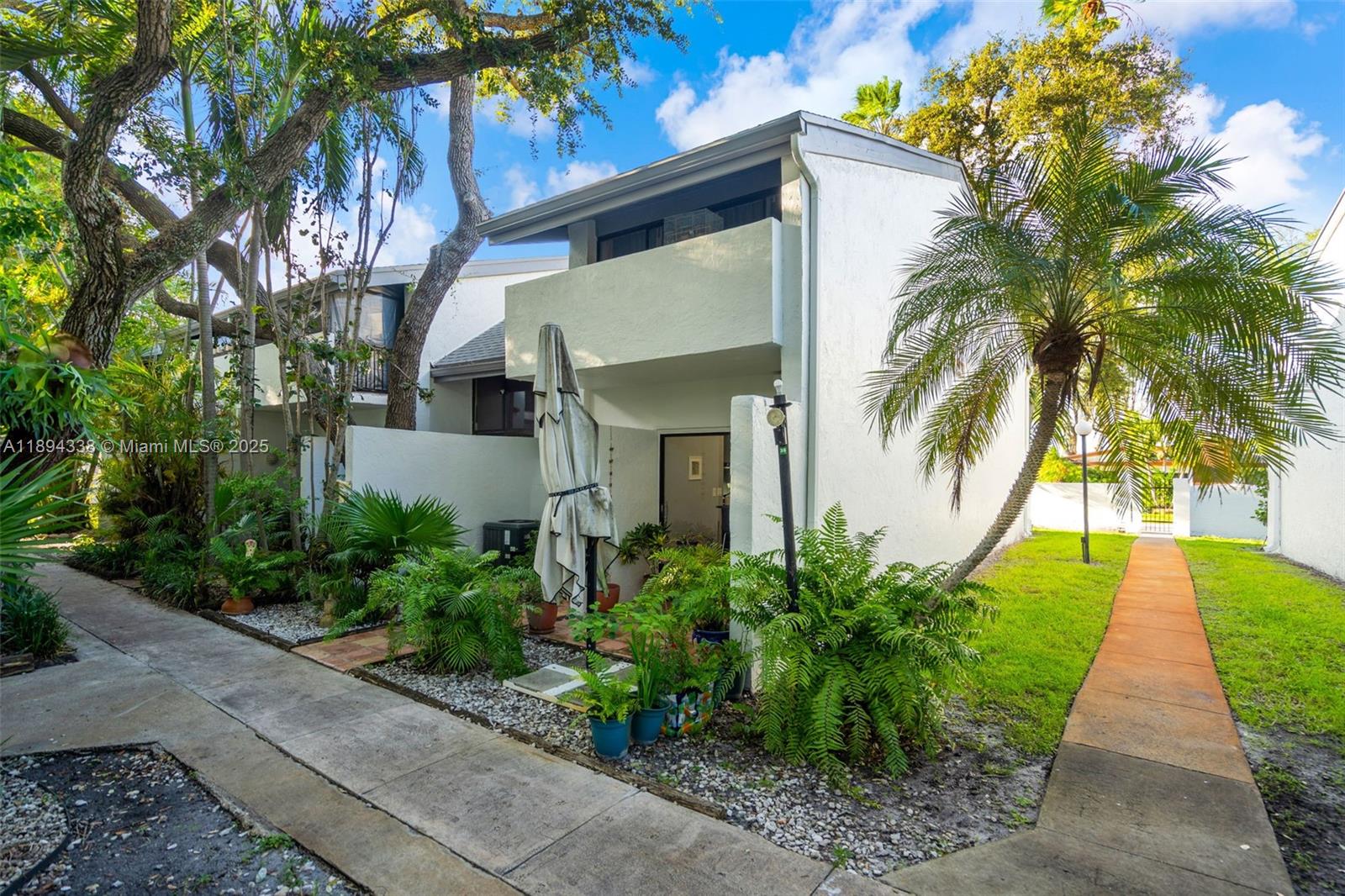 A two-story white townhouse exterior features a small patio, potted plants, and a palm tree — 19440 NE 26th Ave # 54B, Miami FL 33180, MIAMI, FL