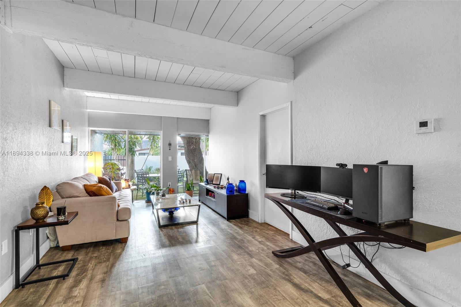 A living room features a beige sofa, a computer desk, and sliding glass doors to a patio — 19440 NE 26th Ave # 54B, Miami FL 33180, MIAMI, FL