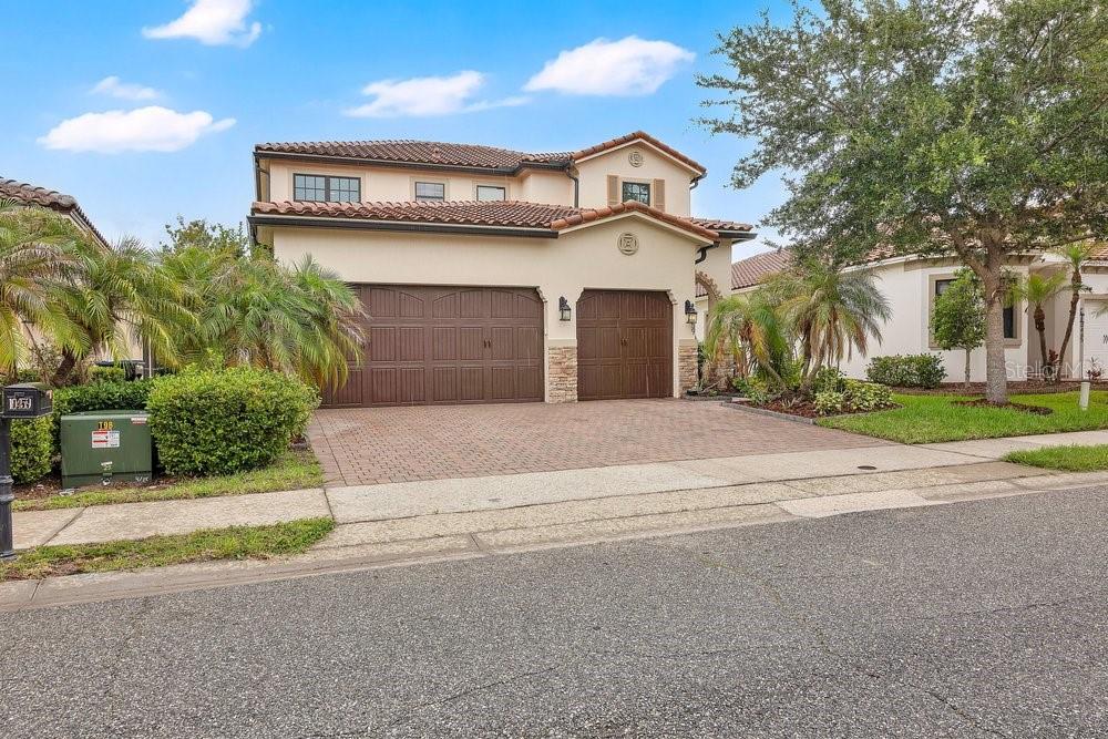 A two-story stucco house with a three-car garage and a paved driveway — 10459 STAPELEY DRIVE, ORLANDO, FL