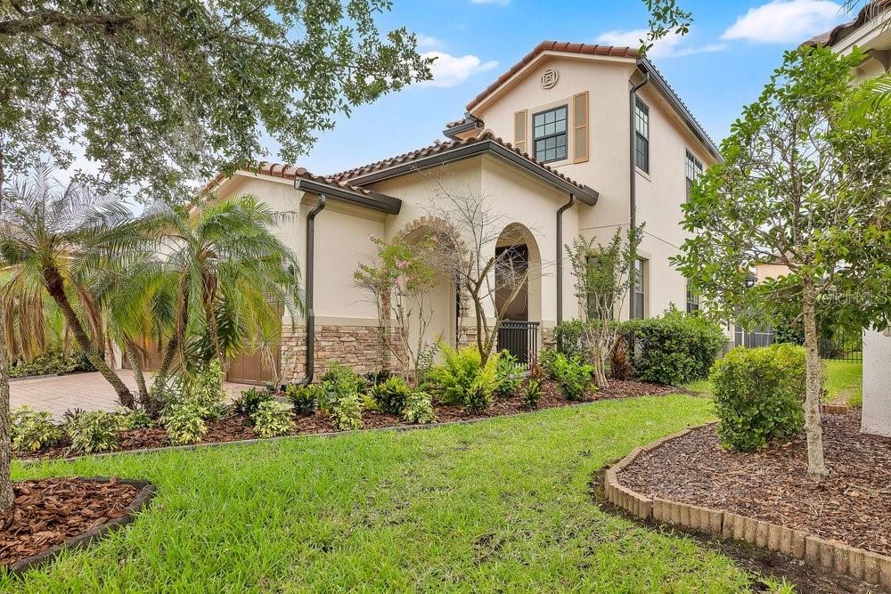 A two-story stucco house with a stone facade, arched entryway, and a landscaped front yard — 10459 STAPELEY DRIVE, ORLANDO, FL