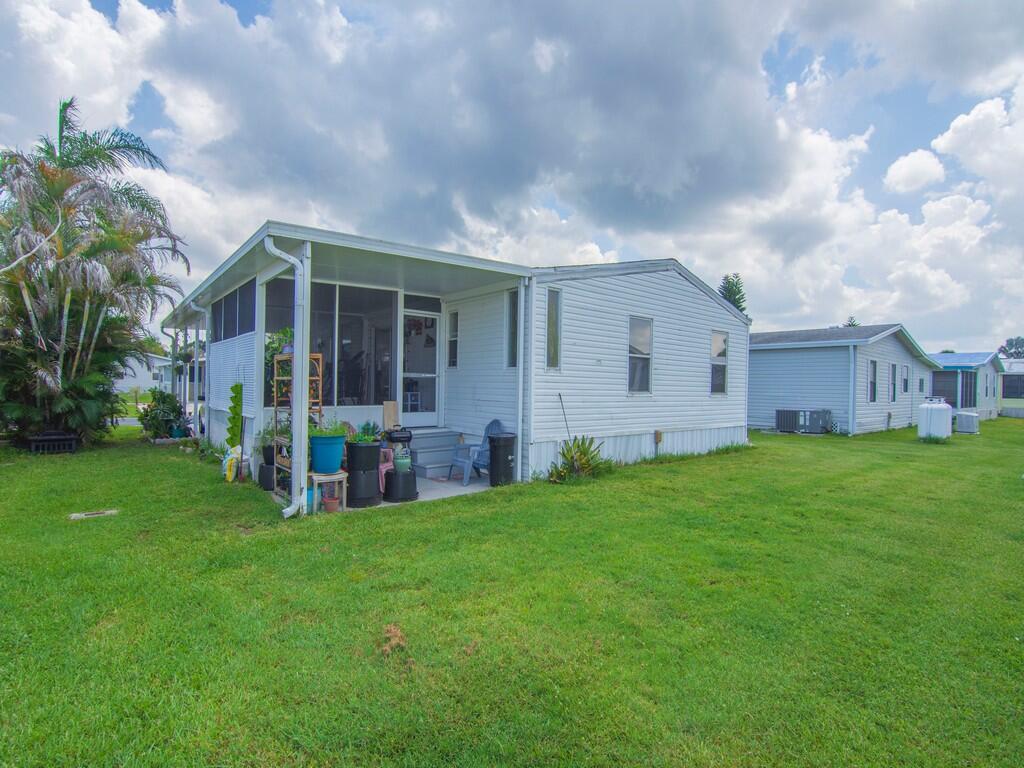 A white mobile home with a screened-in porch sits on a grassy lot — 4697 SE Copperwood Terrace, Stuart FL 34997, STUART, FL