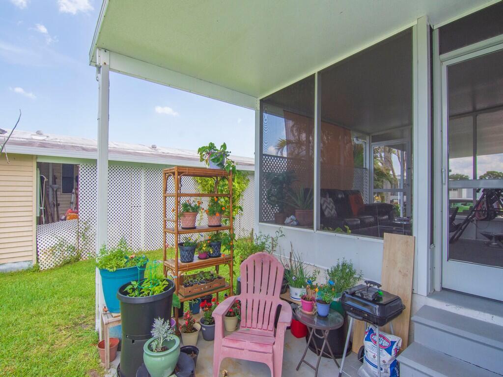 A patio area features a pink chair, a bamboo plant stand, and a screened-in porch — 4697 SE Copperwood Terrace, Stuart FL 34997, STUART, FL