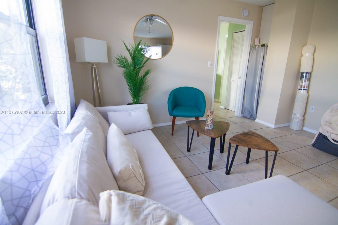 A living room features a white sofa, two small triangular tables, and a teal chair — 753 Michigan Ave # 2D, Miami Beach FL 33139, MIAMI BEACH, FL