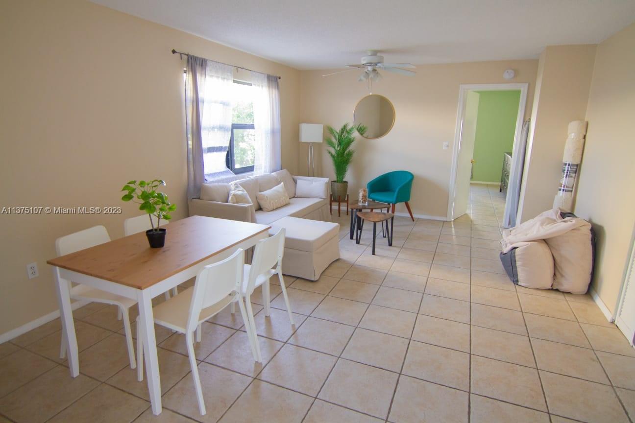A living and dining area features tile flooring, a sectional sofa, and a wooden table — 753 Michigan Ave # 2D, Miami Beach FL 33139, MIAMI BEACH, FL