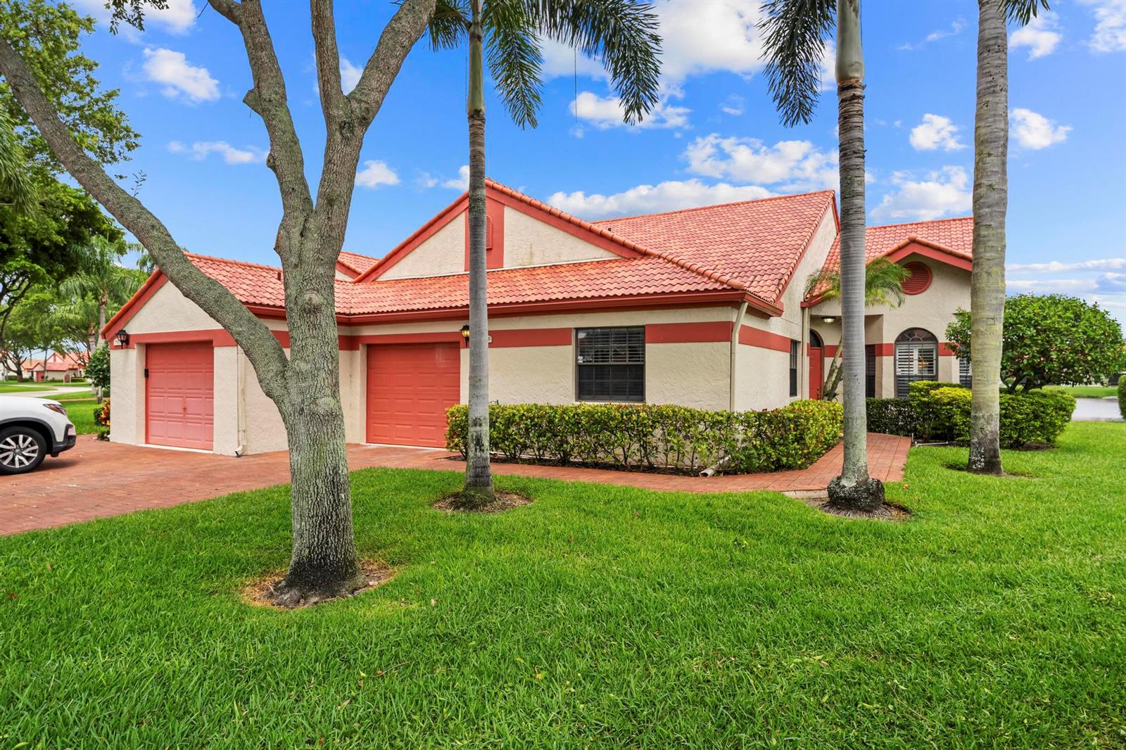A single-story house with a red tile roof, two garage doors, and palm trees — 7792 Lexington Club Boulevard # B, Delray Beach FL 33446, DELRAY BEACH, FL