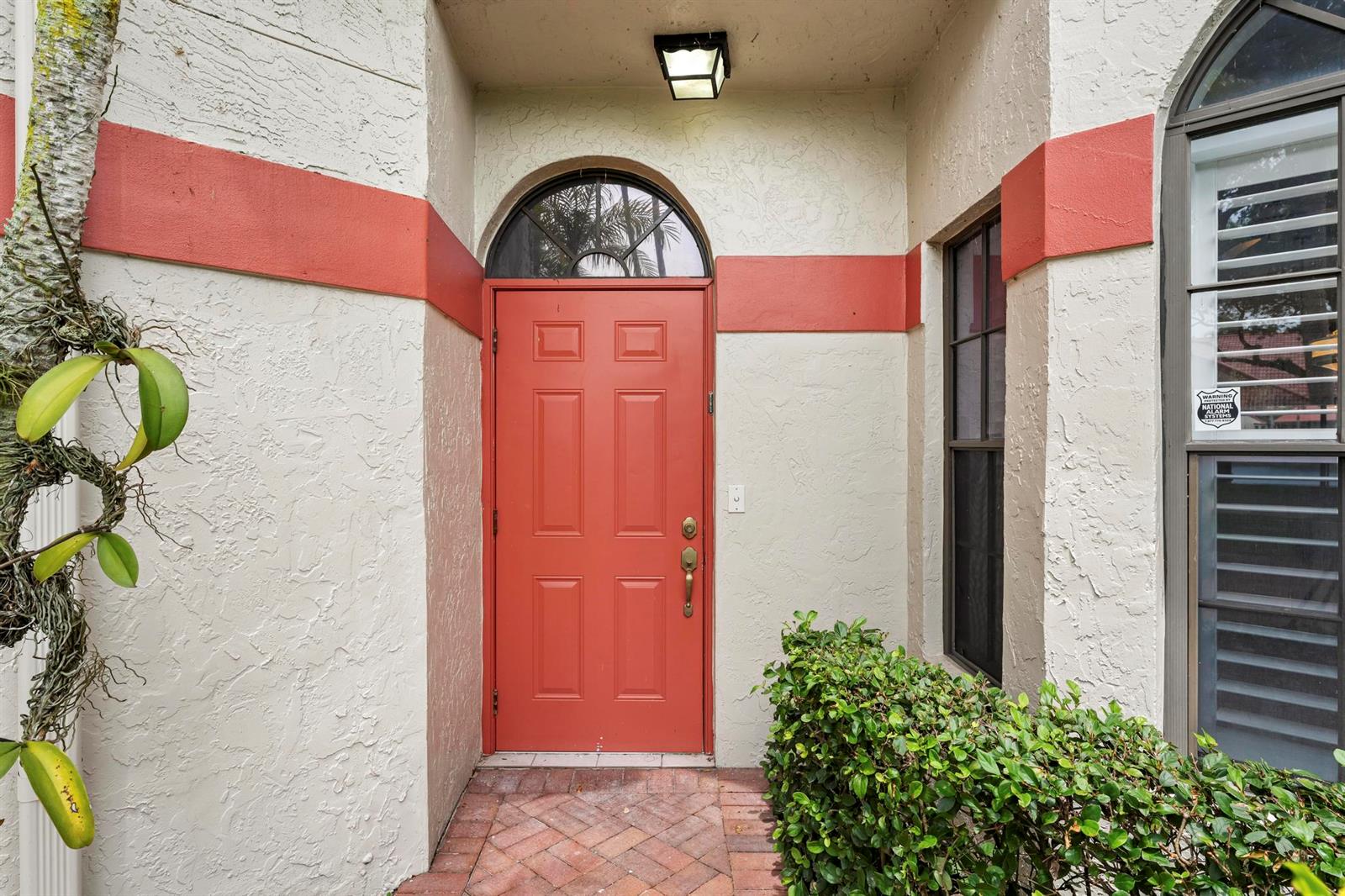 A red front door with a transom window is set in a stucco entryway — 7792 Lexington Club Boulevard # B, Delray Beach FL 33446, DELRAY BEACH, FL