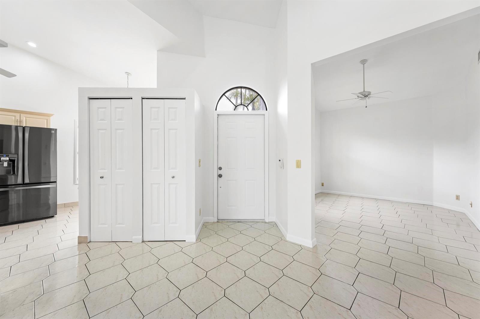 A tiled entryway features a white front door with a transom window and two closets — 7792 Lexington Club Boulevard # B, Delray Beach FL 33446, DELRAY BEACH, FL