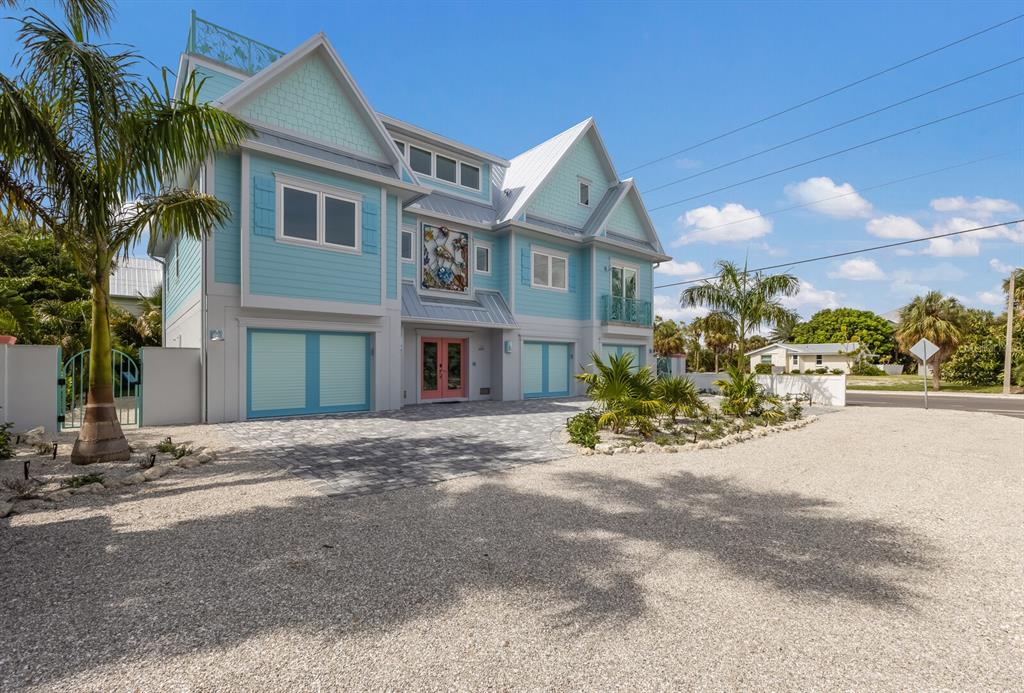 A light blue, multi-story coastal home features a pink front door and gravel driveway — 118 MANGROVE AVENUE, ANNA MARIA, FL