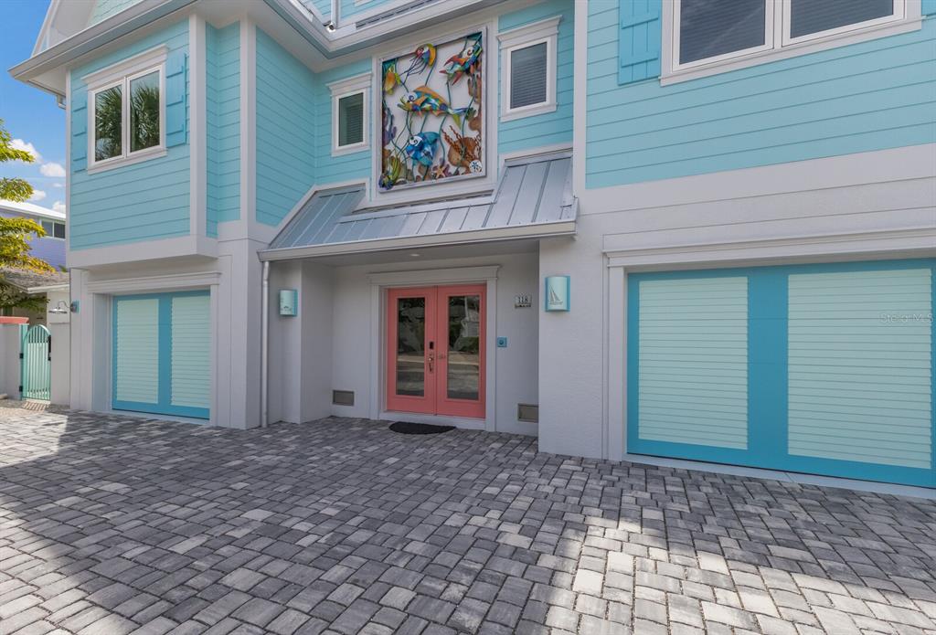 The exterior of a light blue house features a pink double door and two garages — 118 MANGROVE AVENUE, ANNA MARIA, FL
