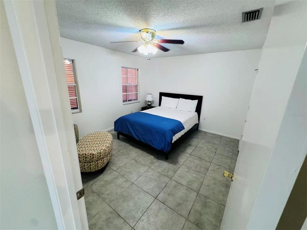 A bedroom with white walls, tile flooring, a ceiling fan, and a queen-sized bed — 3605 57TH  AVENUE DR W, BRADENTON, FL