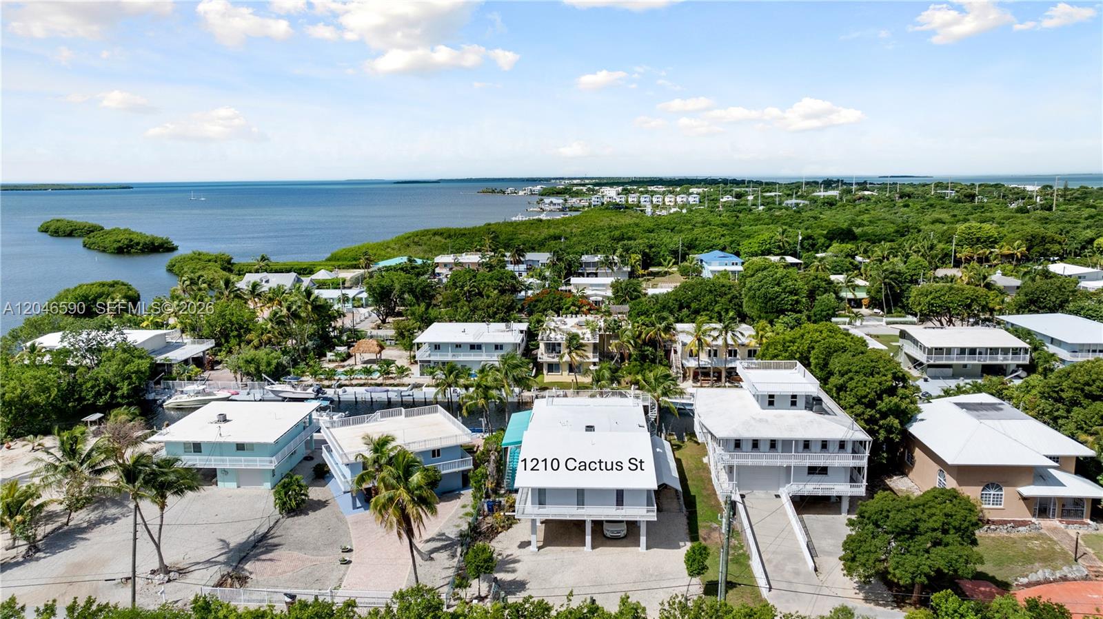 An aerial view shows several multi-story houses near a canal and the ocean — 1210 Cactus St, Key Largo FL 33037, KEY LARGO, FL