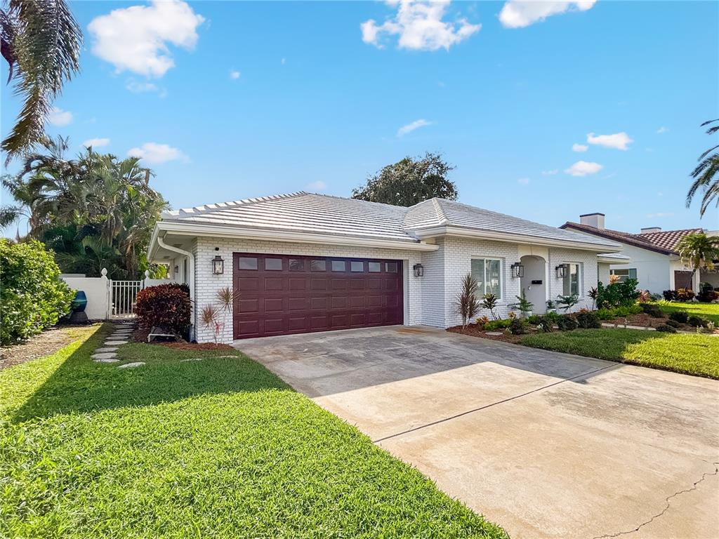 A single-story white brick house features a dark brown garage door and a concrete driveway — 5853 LEELAND STREET S, ST PETERSBURG, FL