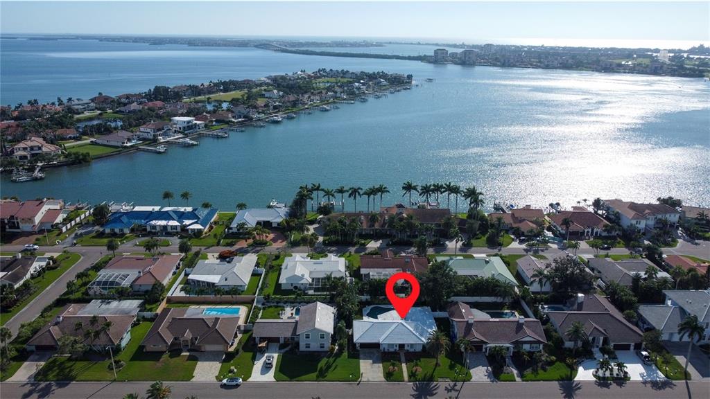 An aerial view shows a residential neighborhood with houses, swimming pools, and a nearby bay — 5853 LEELAND STREET S, ST PETERSBURG, FL
