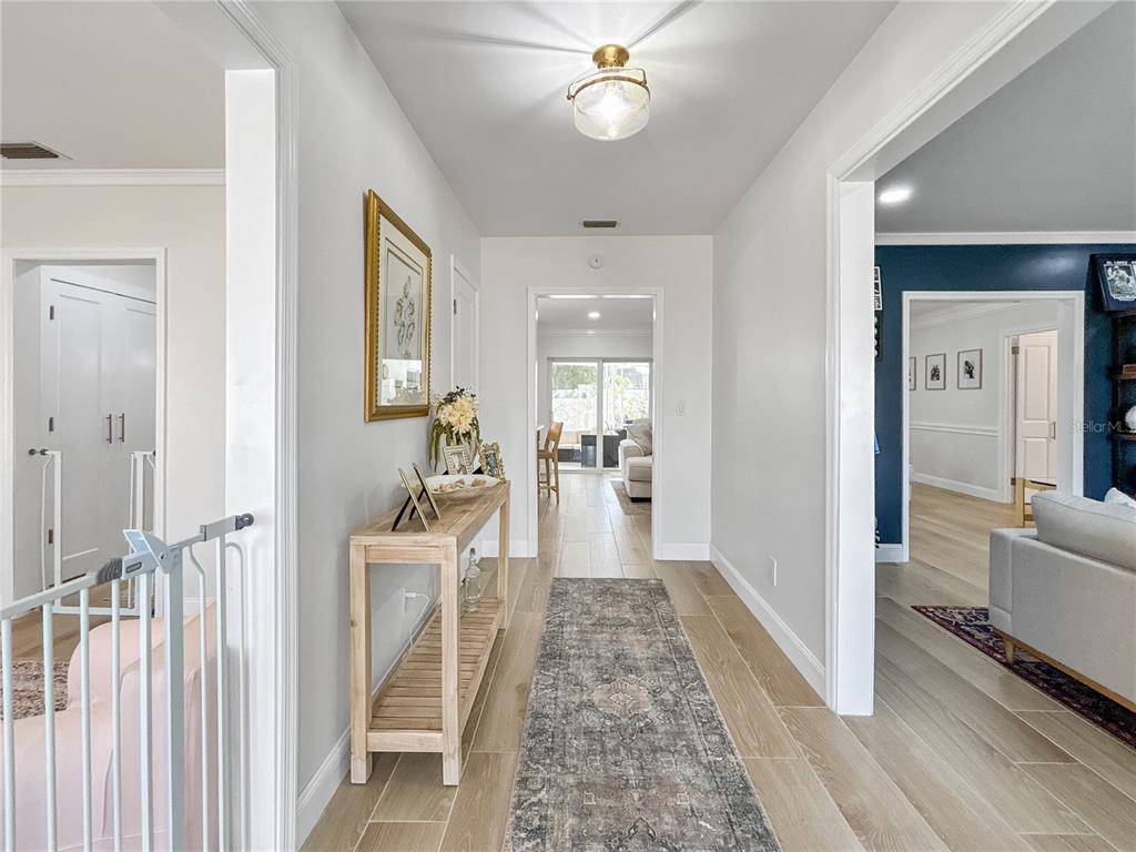 A hallway with light wood-look tile flooring leads to a living area with sliding doors — 5853 LEELAND STREET S, ST PETERSBURG, FL