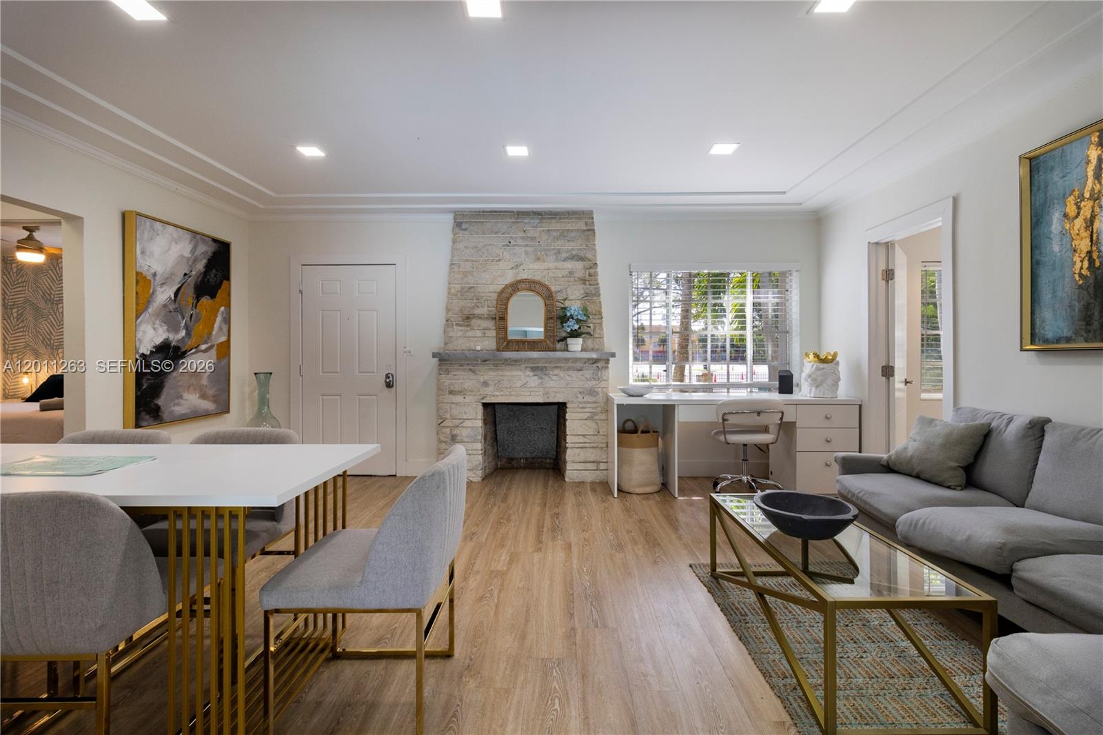 A living and dining area features a stone fireplace, wood-look flooring, and modern furniture — 437 NE 107th St, Miami FL 33161, MIAMI, FL