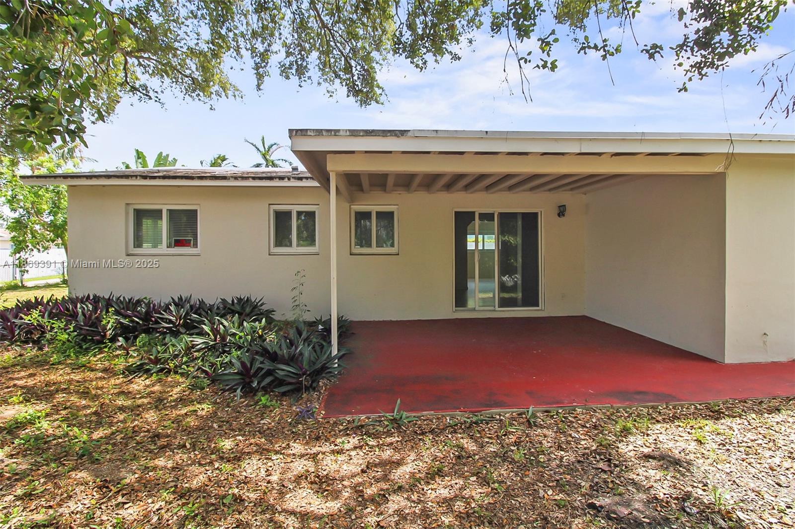 A covered patio with a red concrete floor sits beside a house with sliding doors — 846 NW 10th Ave, Dania Beach FL 33004, DANIA BEACH, FL