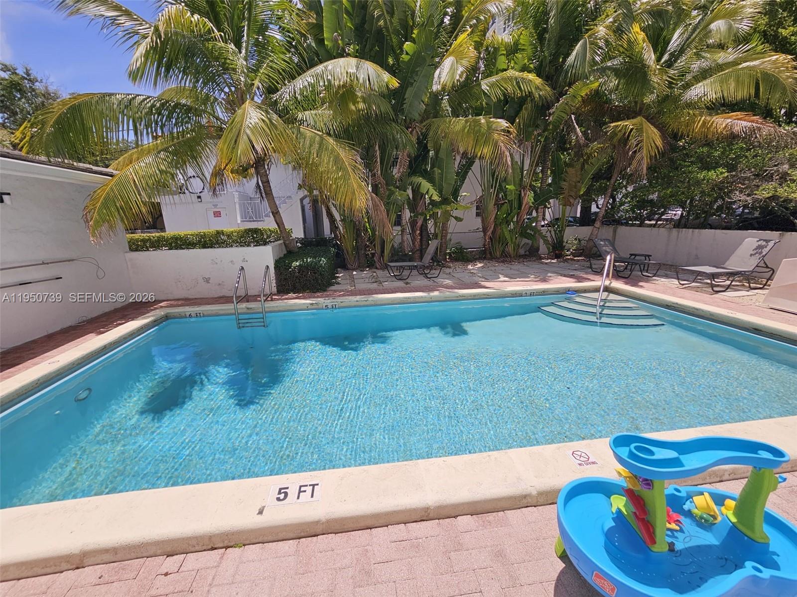 An outdoor swimming pool with a surrounding patio, lounge chairs, and palm trees — 235 Antilla Ave # 4, Coral Gables FL 33134, CORAL GABLES, FL