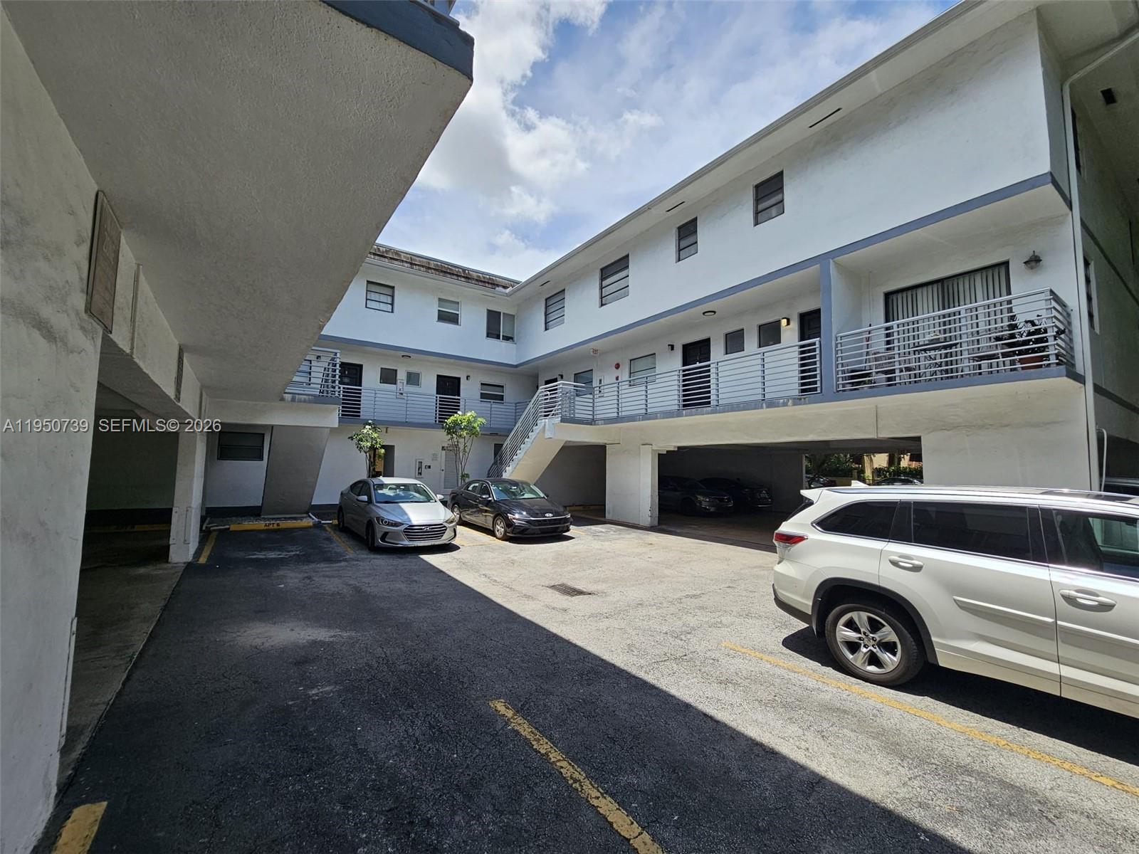 An exterior view of a multi-story apartment building with a parking lot and balconies — 235 Antilla Ave # 4, Coral Gables FL 33134, CORAL GABLES, FL