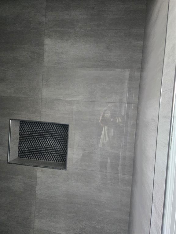 A shower wall features large gray tiles and a recessed niche with black penny tiles — 704 E ORCHID AVENUE, TAMPA, FL