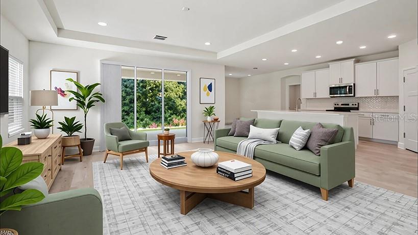 A hallway with light wood flooring leads to an open living area featuring a mirror — 7018 SW 44TH CIRCLE, OCALA, FL