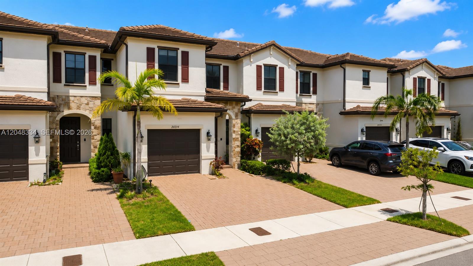 A row of two-story townhouses features beige stucco walls, brown tile roofs, and paved driveways — 10934 W 33rd Way, Hialeah FL 33018, HIALEAH, FL