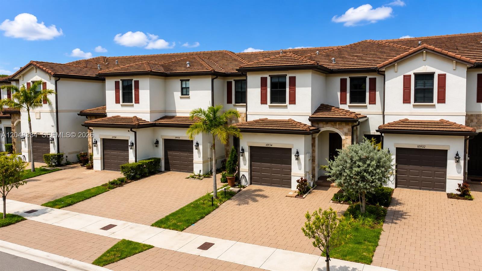 A row of multi-story townhomes with brown garage doors, red shutters, and tiled roofs — 10934 W 33rd Way, Hialeah FL 33018, HIALEAH, FL