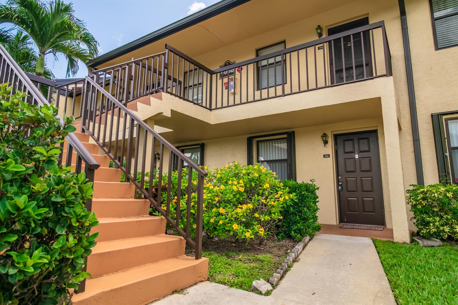 A two-story apartment building exterior features a concrete staircase leading to an upper balcony — 4688 Lucerne Lakes Blvd Boulevard E # 104, Lake Worth FL 33467, LAKE WORTH, FL