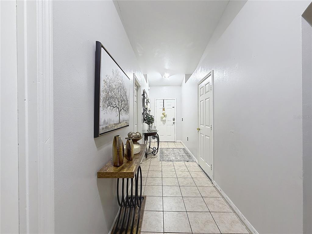 A tiled entryway features a console table, wall art, and a white front door — 522-524 IMPERIAL PLACE, KISSIMMEE, FL