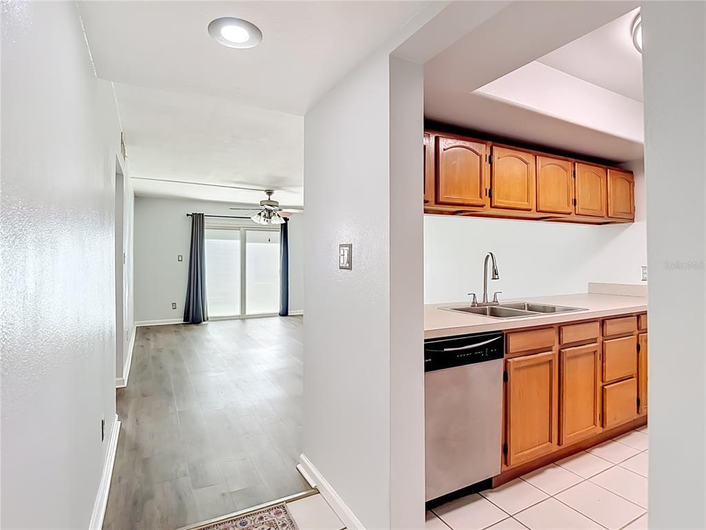 A view from a tiled kitchen into a living area with wood-look flooring — 5820 N CHURCH AVENUE UNIT 164, TAMPA, FL