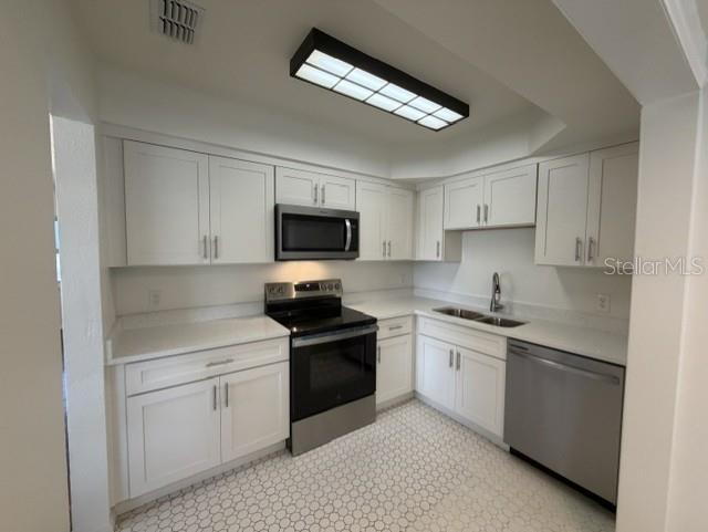 A kitchen features white cabinets, stainless steel appliances, white countertops, and a patterned tile floor — 540 FRANCIS BOULEVARD, LAKELAND, FL
