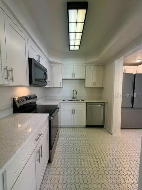 A white kitchen features quartz countertops, stainless steel appliances, and a geometric tiled floor — 540 FRANCIS BOULEVARD, LAKELAND, FL