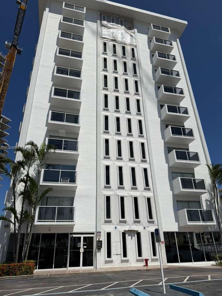A low-angle exterior view of a white multi-story apartment building with stacked balconies — 5313 Collins Ave # 1109, Miami Beach FL 33140, MIAMI BEACH, FL