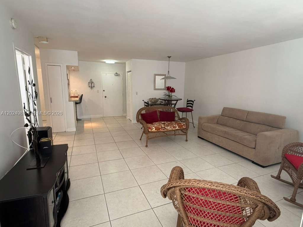 A living and dining area features white tile floors, a beige sofa, and wicker furniture — 5313 Collins Ave # 1109, Miami Beach FL 33140, MIAMI BEACH, FL