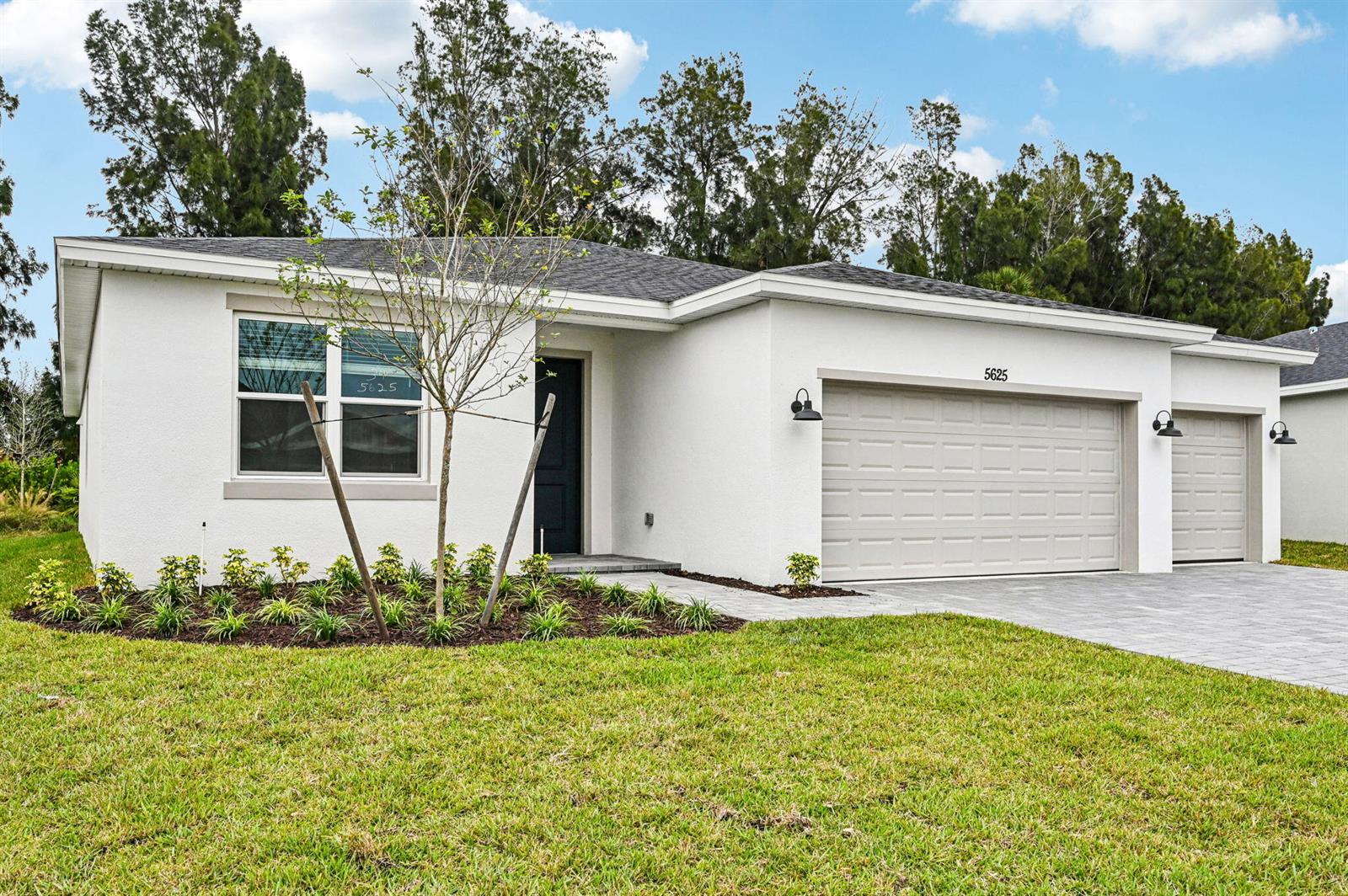 A single-story white house with a two-car garage and a landscaped front yard — 5625 Hampton Park Circle, Vero Beach FL 32966, VERO BEACH, FL