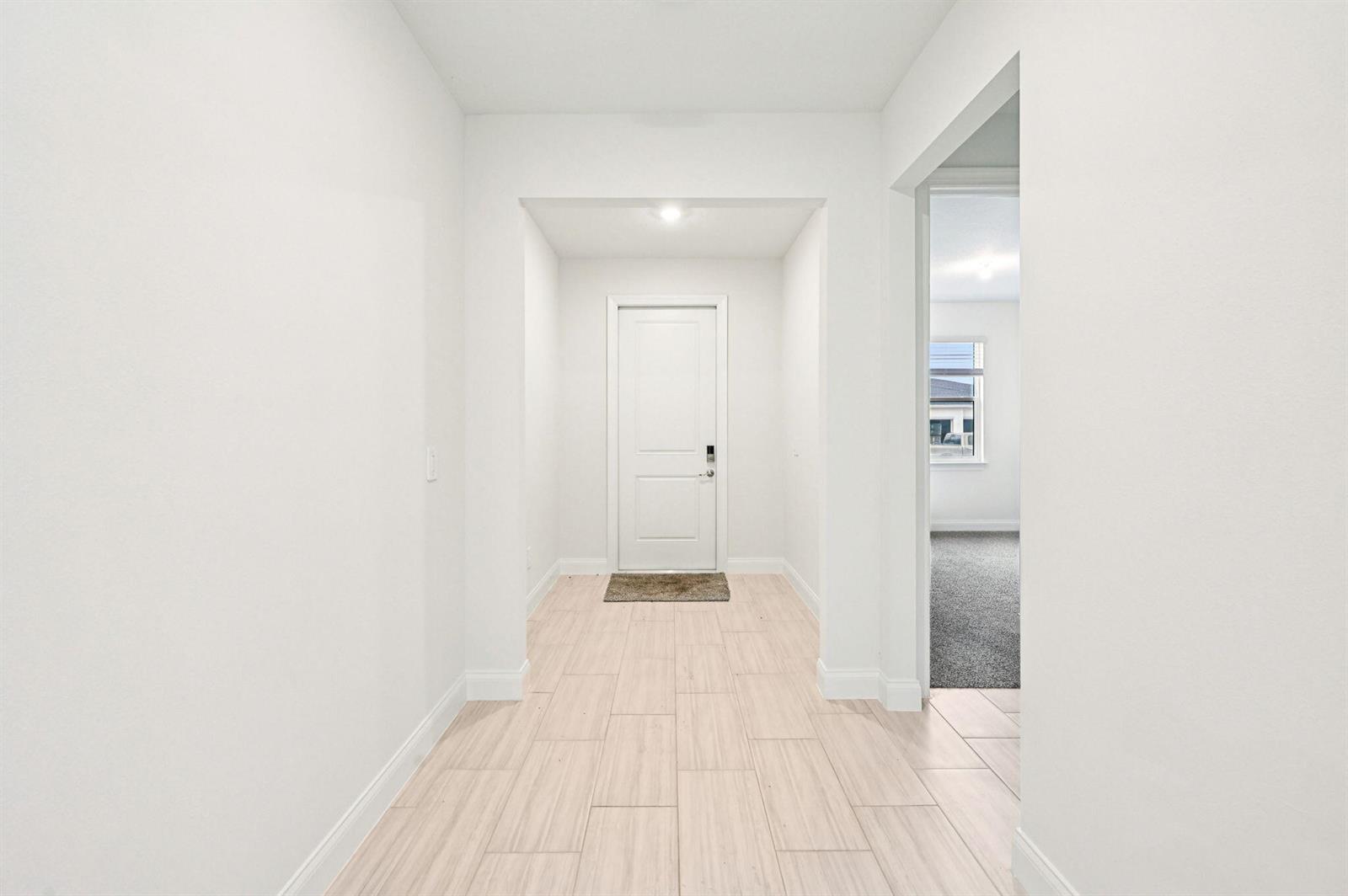 A bright entryway features light-colored tile flooring and a white door at the end — 5625 Hampton Park Circle, Vero Beach FL 32966, VERO BEACH, FL