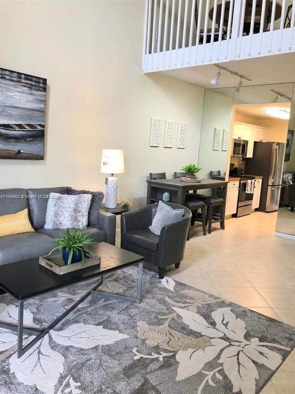 A living room with a gray sofa, armchair, coffee table, and an adjacent dining area — 4812 S Central Blvd # 25, Jupiter FL 33458, JUPITER, FL