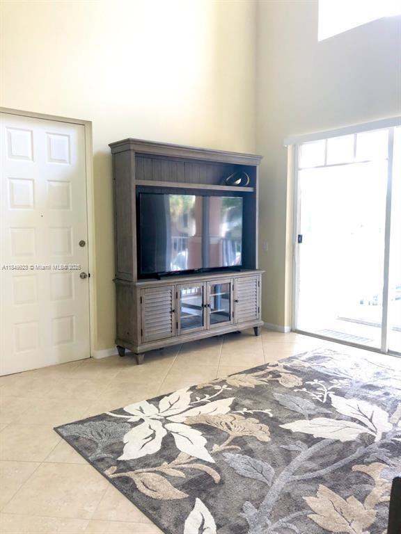 A living room features a large wooden entertainment center, tile flooring, and a sliding glass door — 4812 S Central Blvd # 25, Jupiter FL 33458, JUPITER, FL