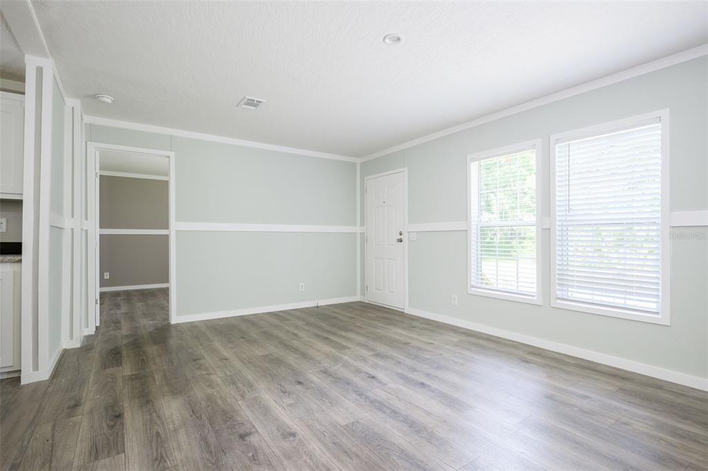 An empty room features light gray walls, white trim, and wood-look laminate flooring — 374 SISCO ROAD, POMONA PARK, FL