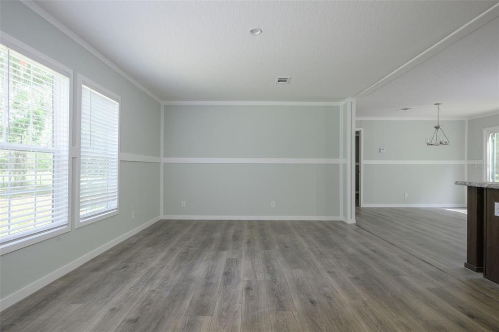 An empty room with light gray walls, white wainscoting, and gray wood-look flooring — 374 SISCO ROAD, POMONA PARK, FL