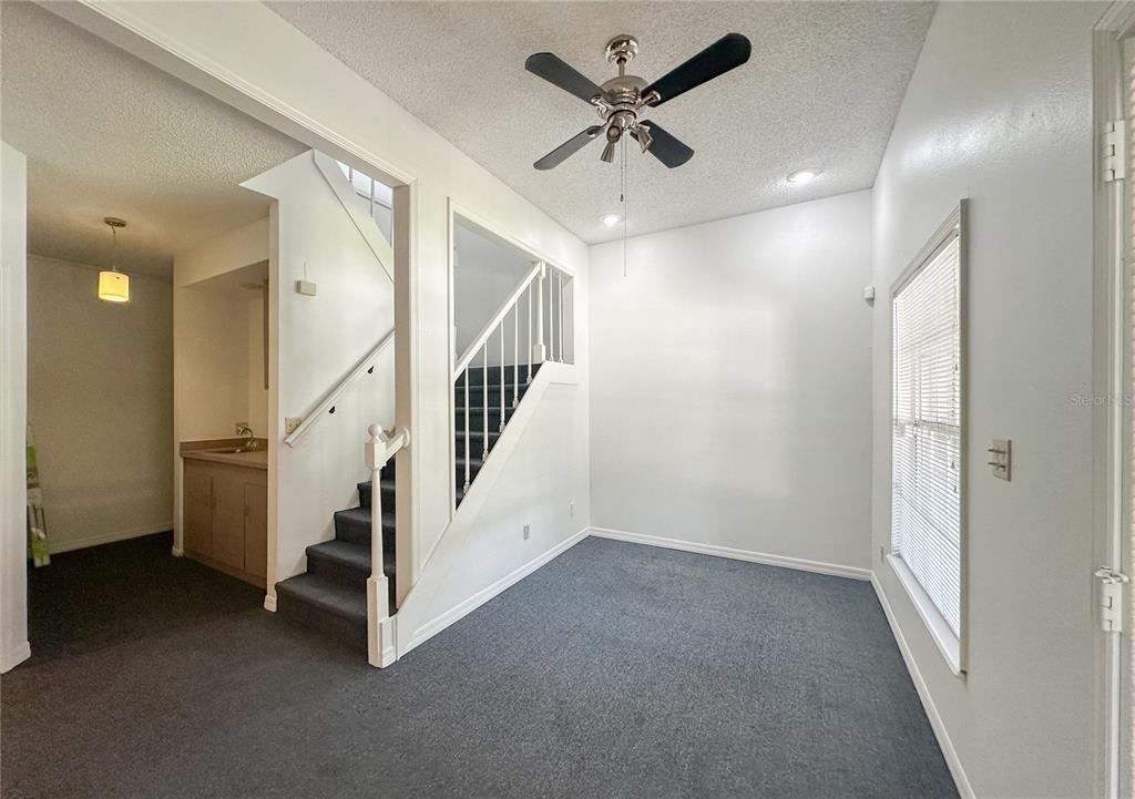 A room with gray carpet, a ceiling fan, a staircase, and a window with blinds — 336 E PLANT STREET, WINTER GARDEN, FL