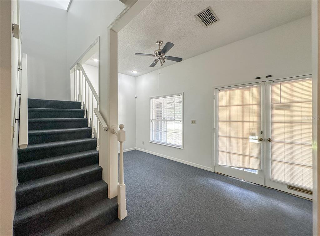 A carpeted room features a staircase with a white railing and double glass doors — 336 E PLANT STREET, WINTER GARDEN, FL