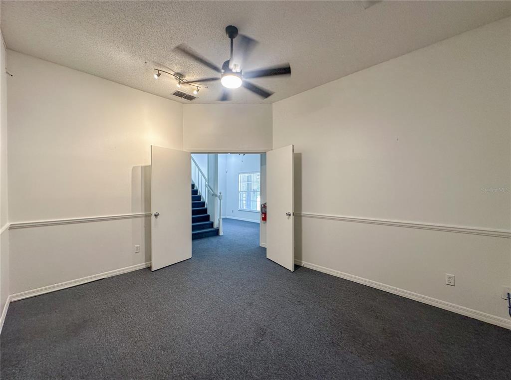 A room with gray carpet, white walls, chair rail molding, and double doors opening to stairs — 336 E PLANT STREET, WINTER GARDEN, FL