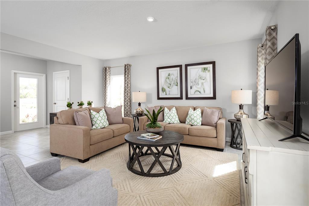 A living room features two tan sofas, a round coffee table, and a television console — 6938 SUNDIAL DRIVE, LAKELAND, FL