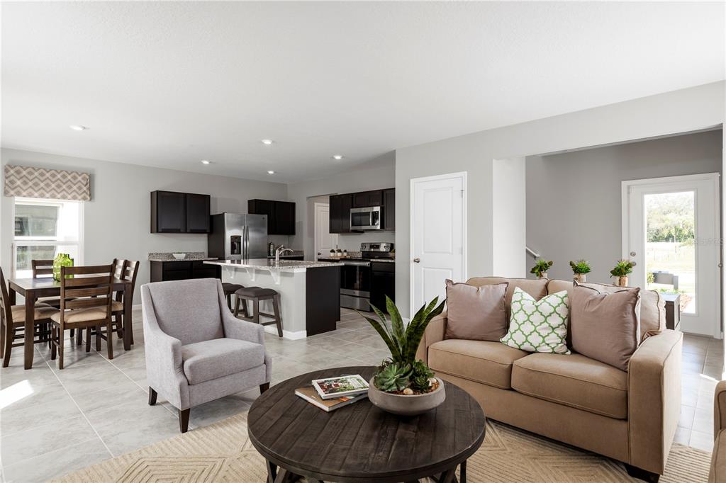An open-concept living room and kitchen featuring dark cabinetry, stainless appliances, and tile flooring — 6938 SUNDIAL DRIVE, LAKELAND, FL